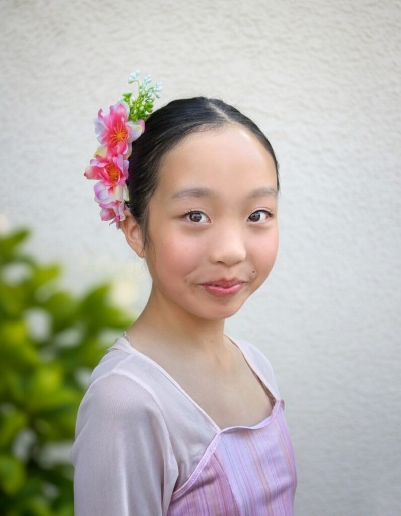 youngest member kristina wearing a flower in her hair dressed in scv chinese dance's iconic pink dress