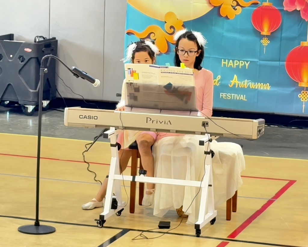 Amy and Ellie performing a duet at the piano